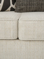 Gros plan sur le tissu texturé beige du canapé Moka de TOCO Meubles avec des coussins décoratifs contrastés