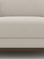 Gros plan sur le revêtement en chenille beige du sofa sectionnel Calvi de TOCO Meubles avec base en bois brun foncé.