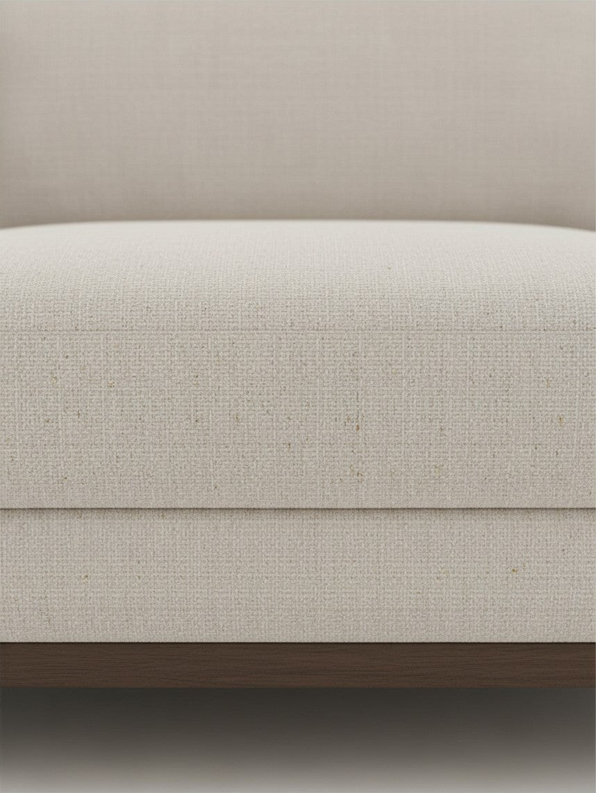 Gros plan sur le revêtement en chenille beige du sofa sectionnel Calvi de TOCO Meubles avec base en bois brun foncé.