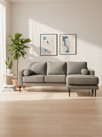 Sofa sectionnel Zela gris anthracite de TOCO Meubles avec méridienne et coussins cylindriques dans un salon moderne.