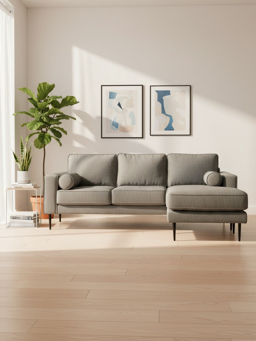 Sofa sectionnel Zela gris anthracite de TOCO Meubles avec méridienne et coussins cylindriques dans un salon moderne.