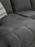 Gros plan sur le tissu texturé gris ardoise du sofa sectionnel Ambee de TOCO Meubles avec coussin à motifs