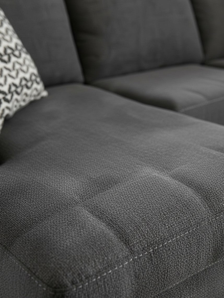 Gros plan sur le tissu texturé gris ardoise du sofa sectionnel Ambee de TOCO Meubles avec coussin à motifs