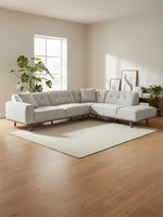 Sofa sectionnel TOCO Meubles Célestin gris clair avec pieds en bois dans un salon moderne et lumineux