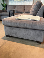 Sofa sectionnel gris TOCO Meubles modèle Colonel avec pouf assorti et texture en tissu dans un salon moderne