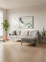 Sofa sectionnel Éden gris de TOCO Meubles avec méridienne dans un salon moderne lumineux avec plantes et cadre
