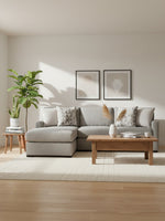 Sofa sectionnel Alba gris de TOCO Meubles dans un salon moderne avec table basse en bois et plantes décoratives