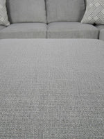Gros plan sur le tissu texturé gris du sofa sectionnel Ugo de TOCO Meubles avec coussins décoratifs à motifs