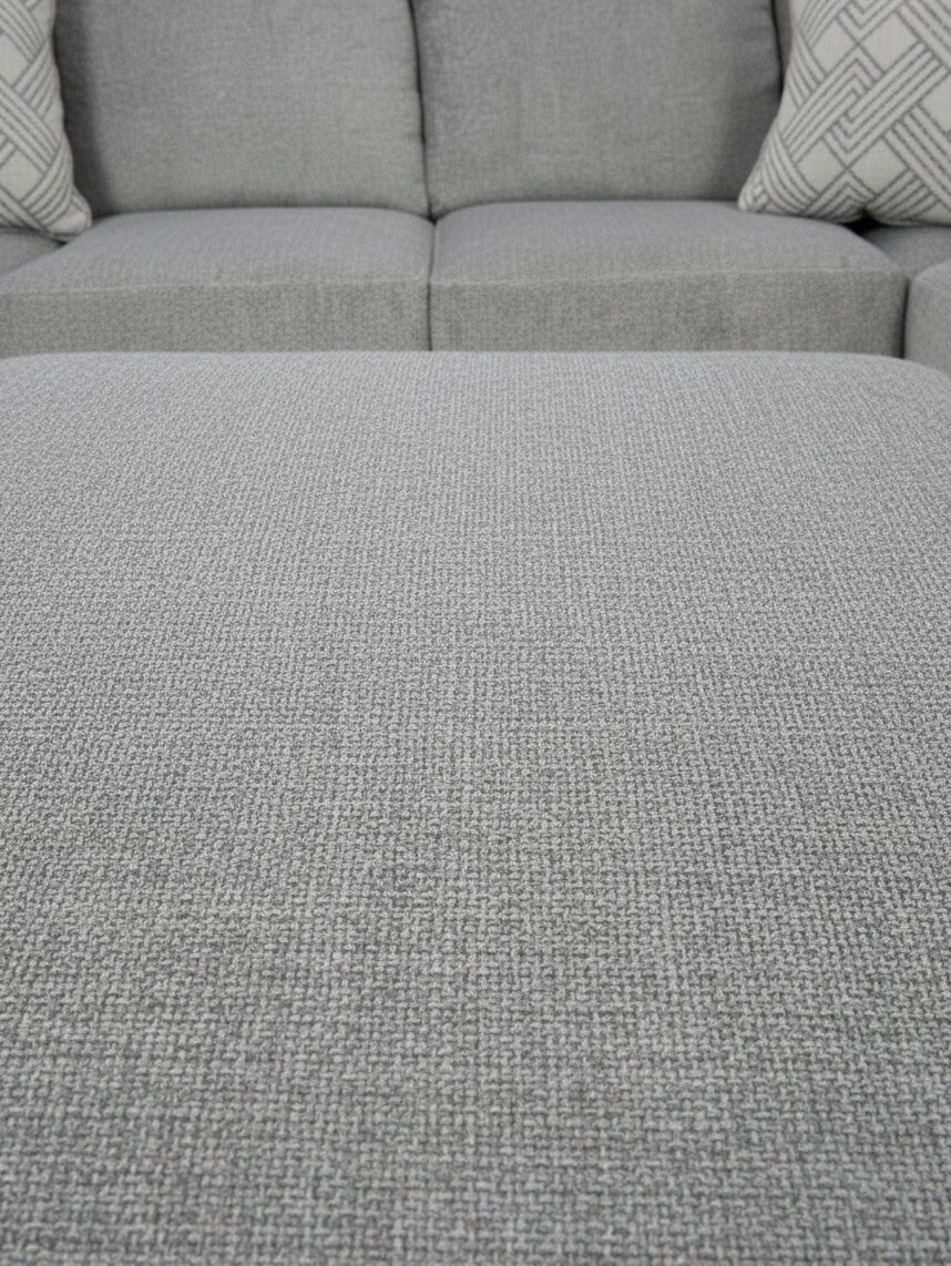 Gros plan sur le tissu texturé gris du sofa sectionnel Ugo de TOCO Meubles avec coussins décoratifs à motifs