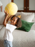 Jeune fille jouant avec un ballon jaune devant le sofa sectionnel Melissa personnalisable de TOCO Meubles