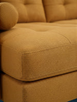 Gros plan sur le tissu texturé moutarde du sofa sectionnel Nyla de TOCO Meubles avec détails capitonnés