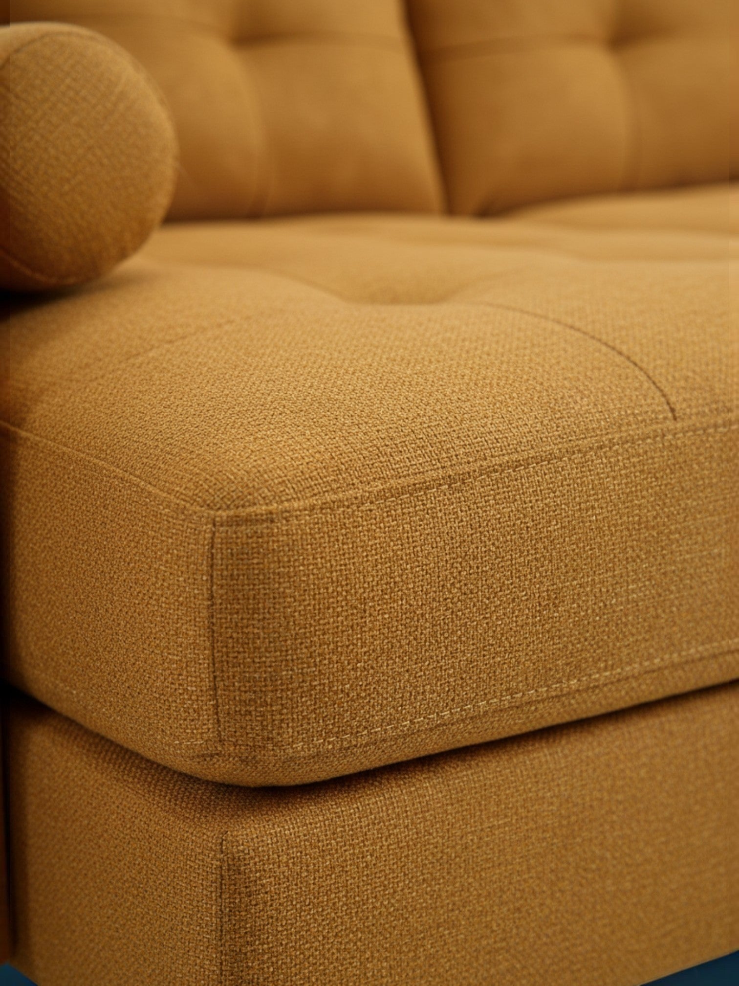 Gros plan sur le tissu texturé moutarde du sofa sectionnel Nyla de TOCO Meubles avec détails capitonnés