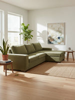 Sofa sectionnel Forest TOCO Meubles en tissu vert olive dans un salon lumineux avec plantes et tapis en jute