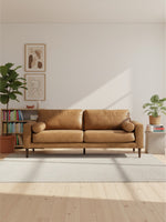 Sofa Telora TOCO Meubles en cuir caramel avec coussins cylindriques dans un salon moderne et lumineux