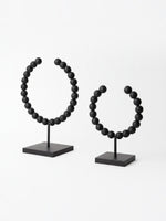 Deux objets décoratifs Tulane TOCO Meubles en forme de sphères brisées avec perles noires mates sur socles carrés.