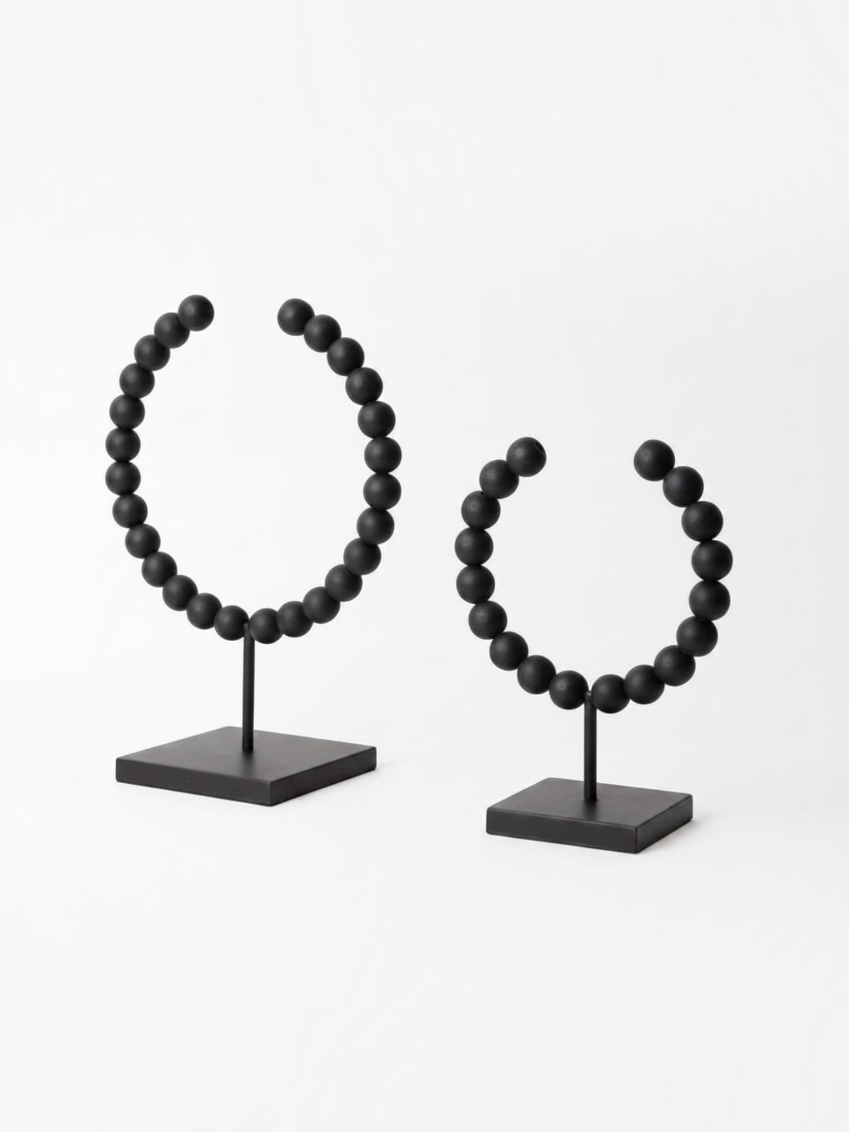 Deux objets décoratifs Tulane TOCO Meubles en forme de sphères brisées avec perles noires mates sur socles carrés.