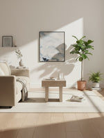 Table d'appoint Elaina en bois clair de TOCO Meubles dans un salon minimaliste avec plante et décoration murale