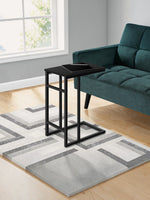 Table d'appoint noire Valcourt de TOCO Meubles au design minimaliste glissée près d'un canapé en velours vert
