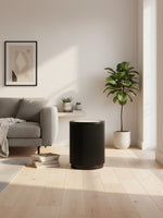 Table d'appoint ronde noire Rayma de TOCO Meubles avec base cannelée dans un salon moderne et lumineux