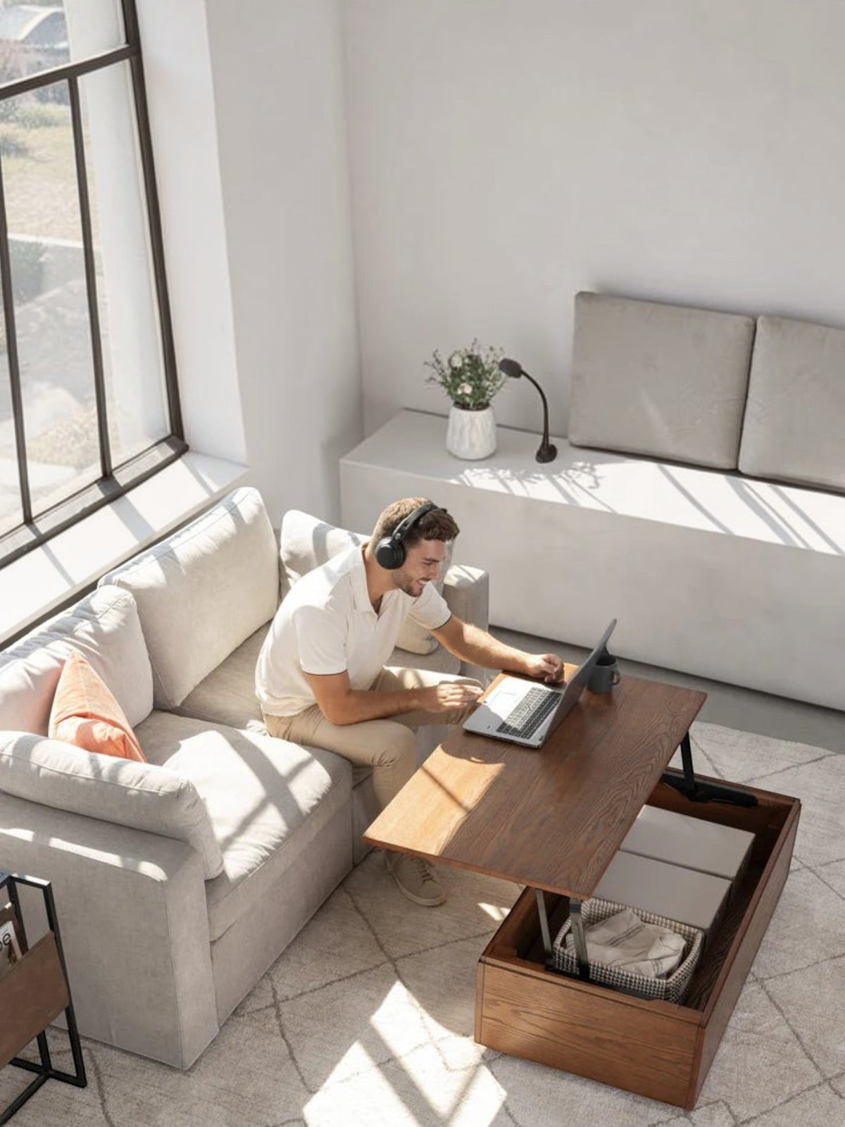 Homme travaillant sur un ordinateur portable sur une table basse relevable en noyer américain TOCO Meubles