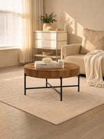 Table basse ronde TOCO Meubles Belcourt avec plateau en bois texturé et pieds fins en métal noir dans un salon