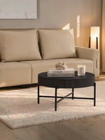 Table basse ronde noire TOCO Meubles avec plateau texturé et pieds fins en métal dans un salon contemporain