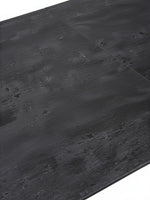 Gros plan sur le plateau en céramique noire texturée de la table de salle à manger Liora par TOCO Meubles