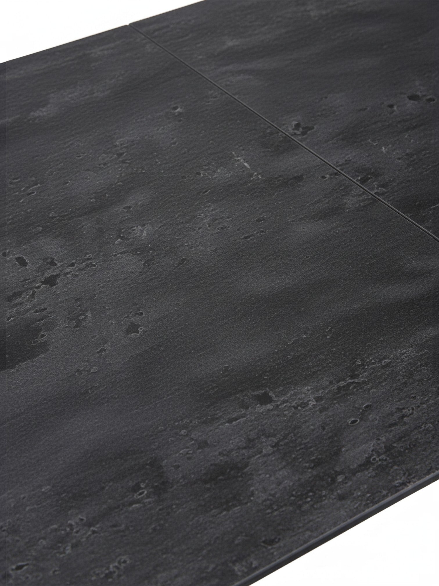 Gros plan sur le plateau en céramique noire texturée de la table de salle à manger Liora par TOCO Meubles