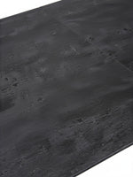 Gros plan sur le plateau en céramique noire texturée de la table de salle à manger Liora par TOCO Meubles