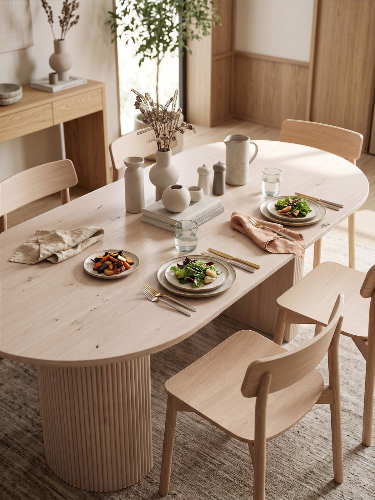 Table de cuisine TOCO Meubles Kamilia ovale en bois clair avec pieds cannelés dans une salle à manger lumineuse
