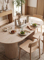 Table de cuisine ovale en bois clair TOCO Meubles avec pieds cannelés dans une salle à manger minimaliste