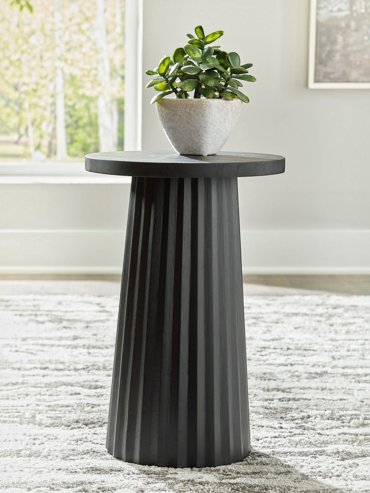 Table d'appoint Ada TOCO Meubles en bois noir avec base cannelée sculpturale et plante verte.