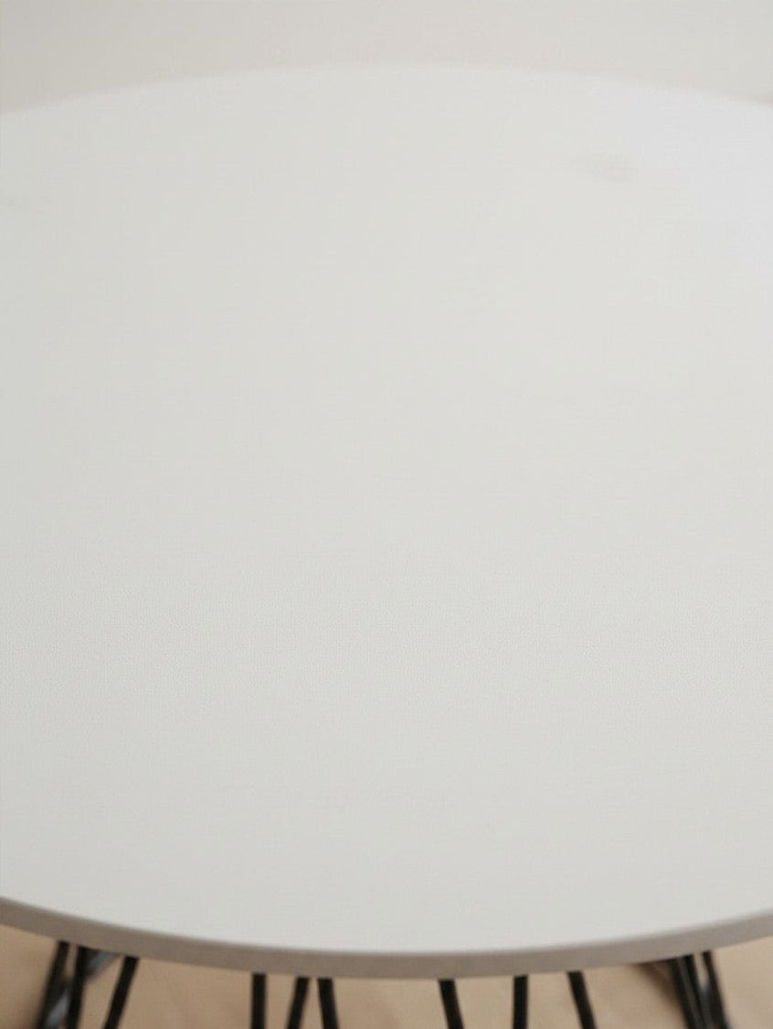 Gros plan sur le plateau blanc mat de la table de salle à manger Livia par TOCO Meubles avec pieds en métal noir