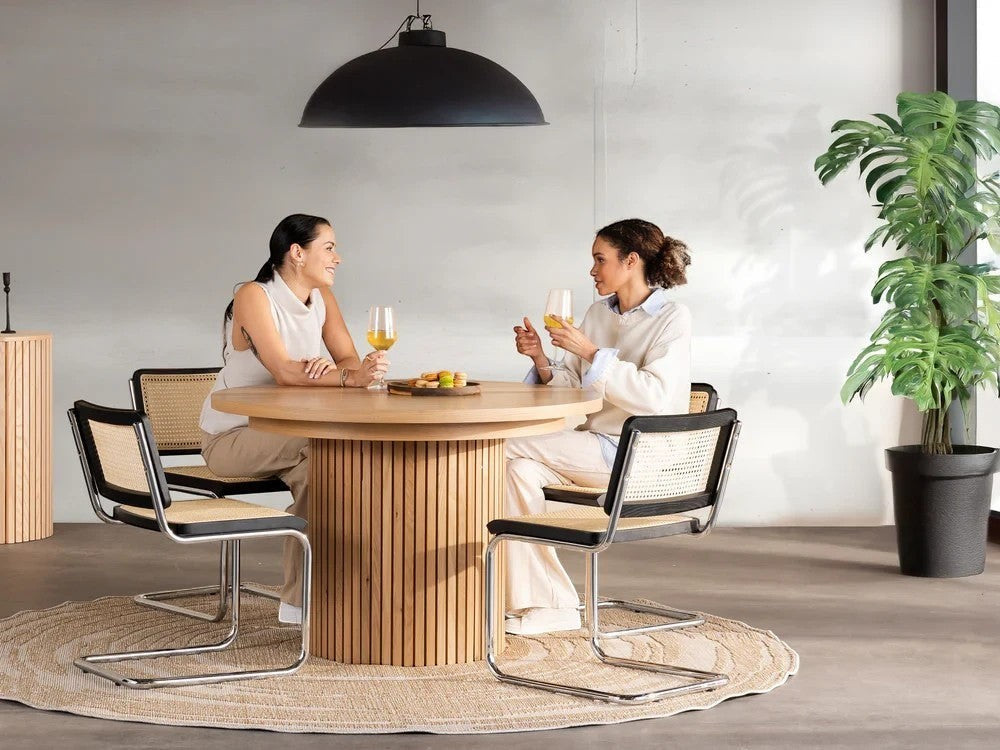 Table de salle à manger ronde en bois clair de TOCO Meubles, style scandinave, avec deux femmes assises.