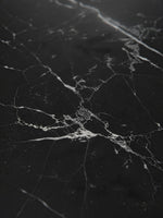 Gros plan sur le plateau en marbre noir veiné de blanc de la table de salle à manger Remy par TOCO Meubles
