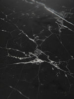 Gros plan sur le plateau en marbre noir veiné de blanc de la table de salle à manger Remy par TOCO Meubles