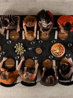 Table de salle à manger TOCO Meubles Transformer Table ronde en bois fumé, disposée pour un repas avec des convives.