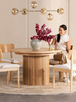 Table de salle à manger ronde en chêne scandinave TOCO Meubles avec pieds cannelés, 4 chaises en bois clair et tapis rond.