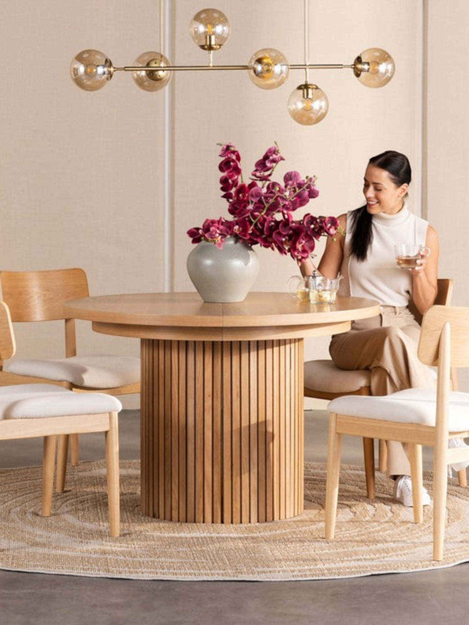 Table de salle à manger ronde en chêne scandinave TOCO Meubles avec pieds cannelés, 4 chaises en bois clair et tapis rond.