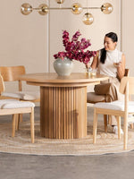 Table de salle à manger ronde en chêne scandinave TOCO Meubles avec pieds cannelés, 4 chaises en bois clair et tapis rond.