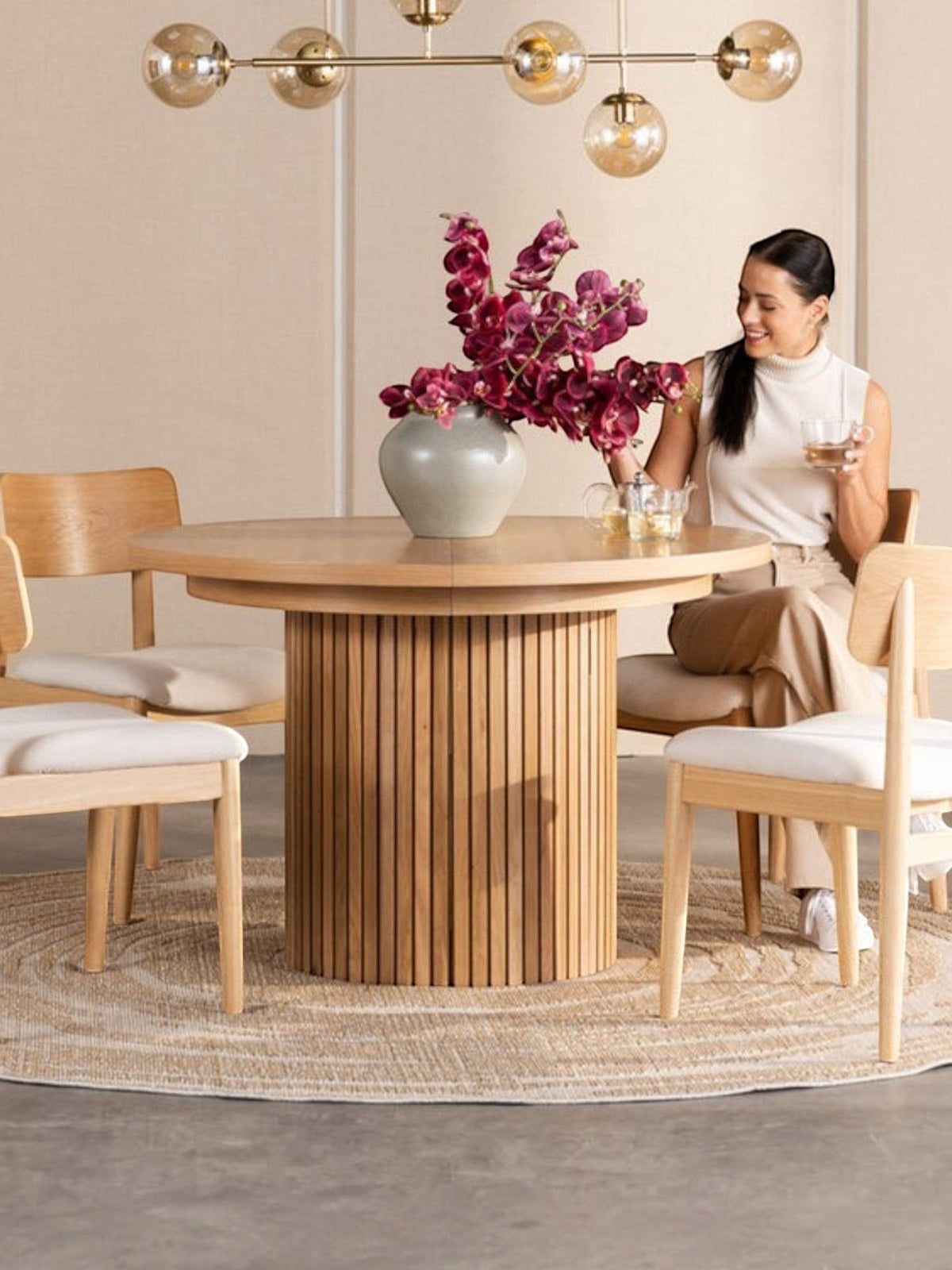 Table de salle à manger ronde en chêne scandinave TOCO Meubles avec pieds cannelés, 4 chaises en bois clair et tapis rond.