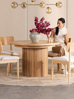 Table de salle à manger ronde en chêne scandinave TOCO Meubles avec pieds cannelés, 4 chaises en bois clair et tapis rond.