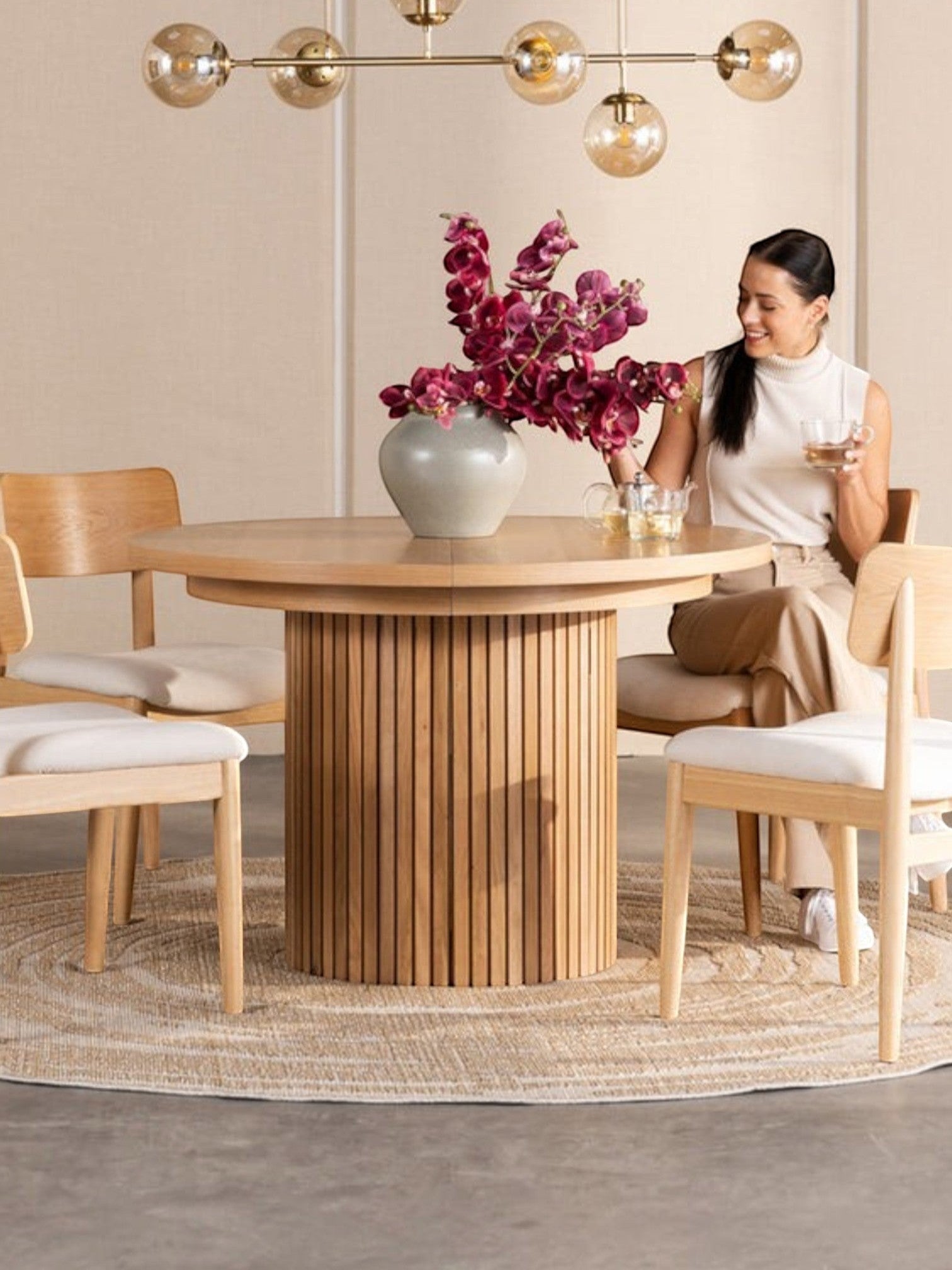 Table de salle à manger ronde en chêne scandinave TOCO Meubles avec pieds cannelés, 4 chaises en bois clair et tapis rond.