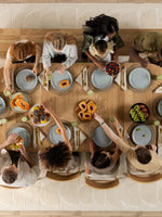 Table de salle à manger ronde en chêne scandinave TOCO Meubles, avec 10 personnes attablées pour un repas.
