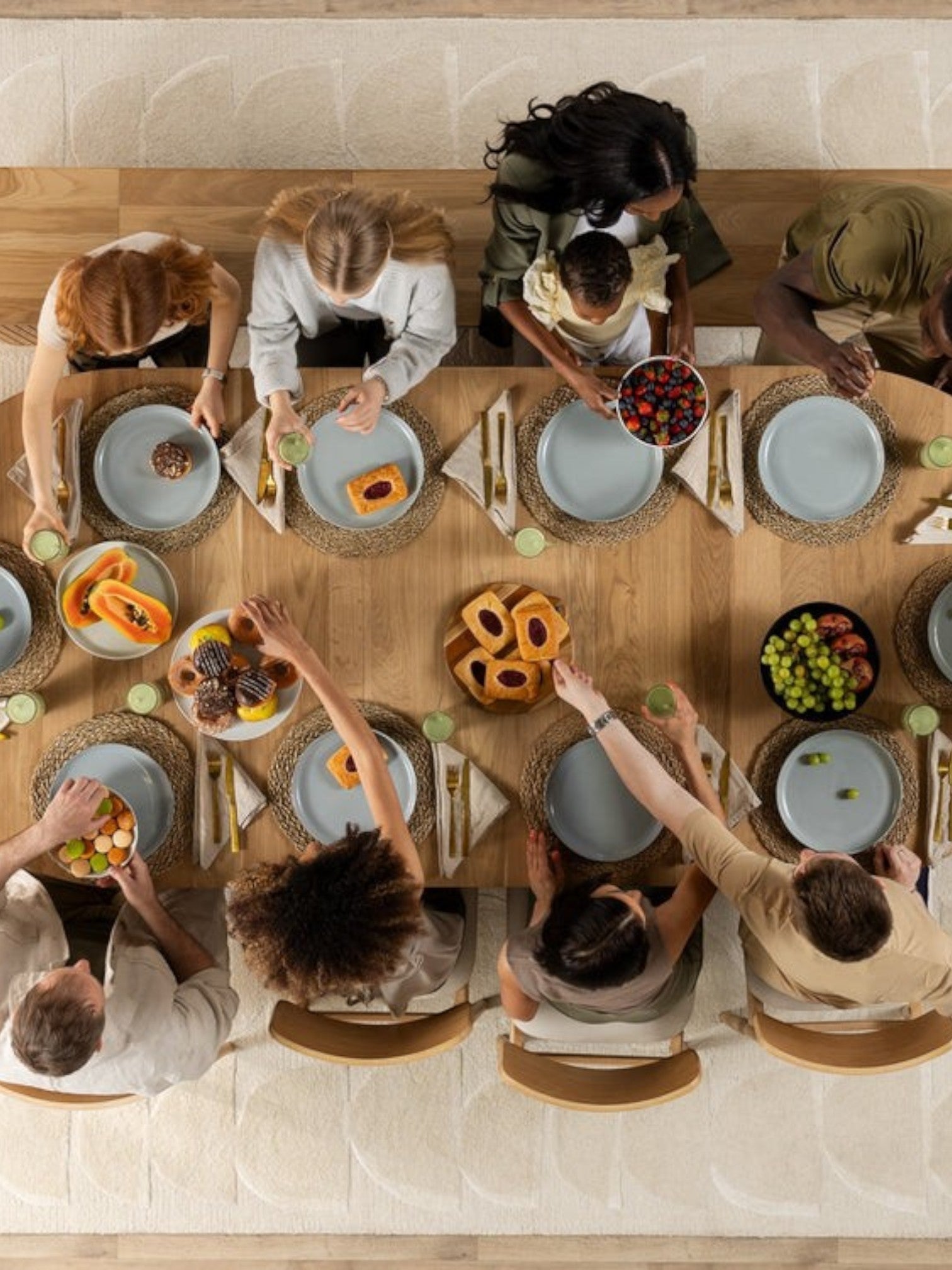 Table de salle à manger ronde en chêne scandinave TOCO Meubles, avec 10 personnes attablées pour un repas.
