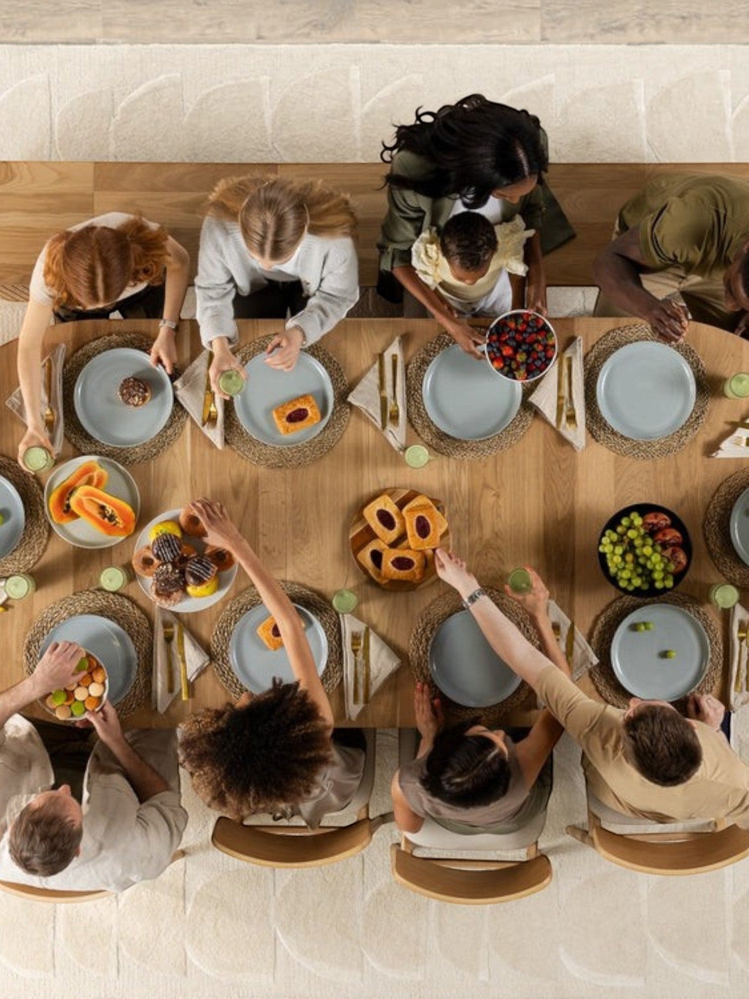Table de salle à manger ronde en chêne scandinave TOCO Meubles, avec 10 personnes attablées pour un repas.