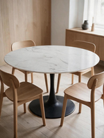 Table ronde TOCO Meubles Zila avec plateau effet marbre blanc et base centrale en métal noir mat entourée de chaises