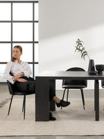 Table de salle à manger TOCO Meubles en bois fumé, design extensible, avec 4 chaises noires et une femme assise.