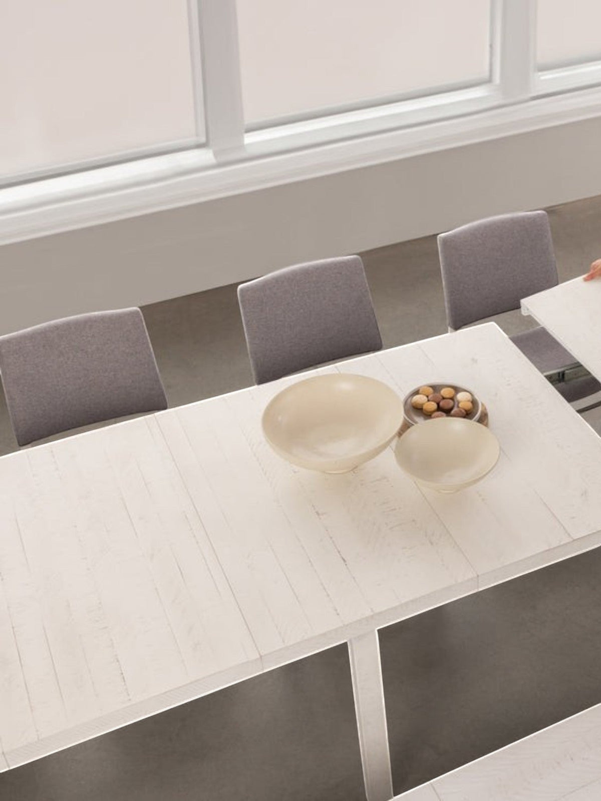 Table de salle à manger extensible en bois blanc TOCO Meubles, une femme ajoute une rallonge. Style moderne.