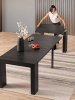 Femme installant une rallonge sur la table de salle à manger extensible TOCO Meubles en bois hickory fumé noir